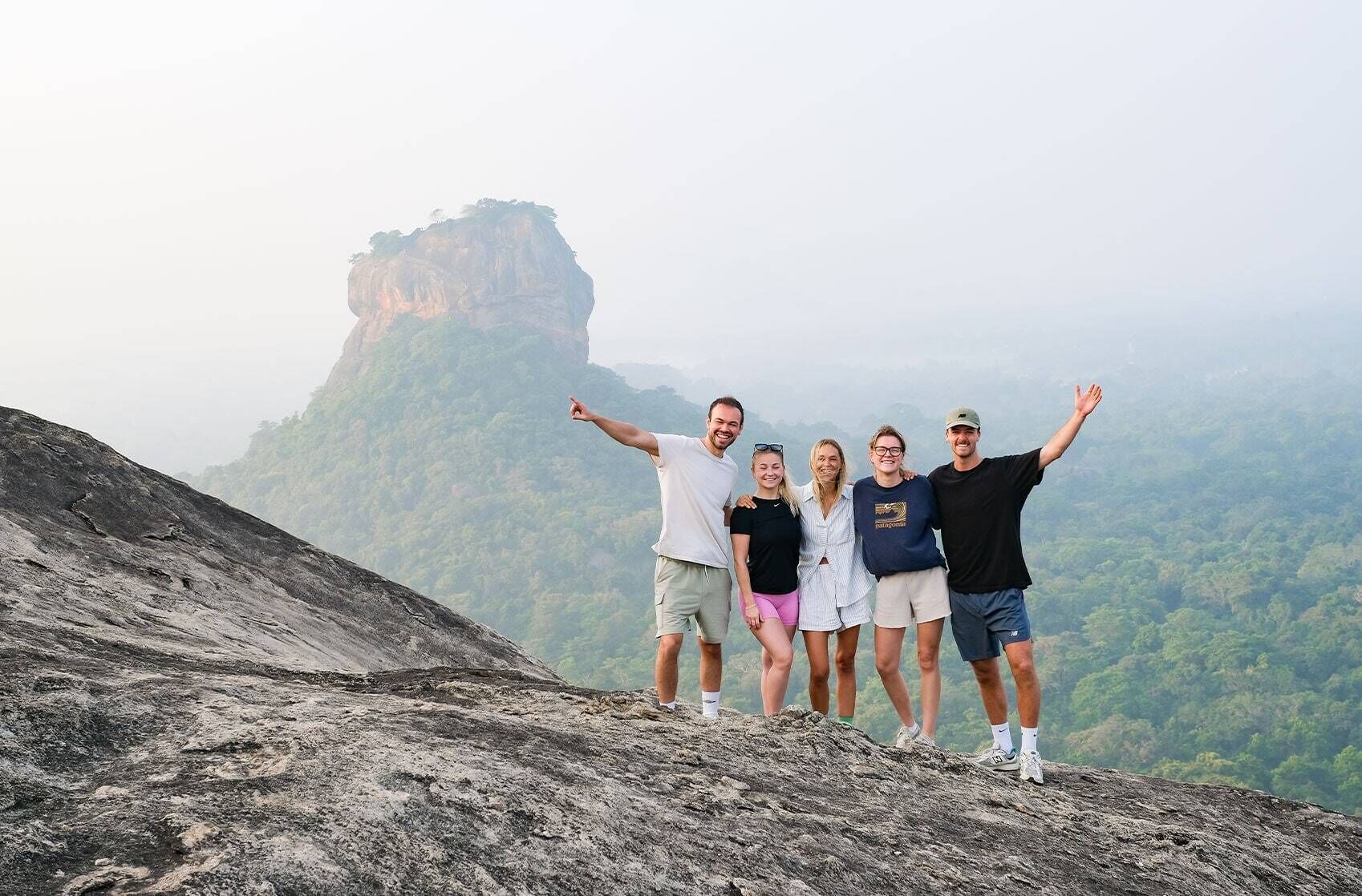 Un grupo de personas sobre un afloramiento rocoso, con un paisaje montañoso al fondo.