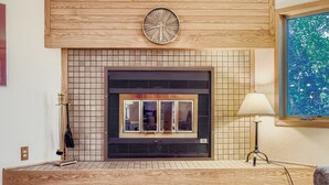 Une cheminée moderne, agrémentée de carreaux décoratifs, avec une horloge au-dessus et une lampe sur le côté droit.