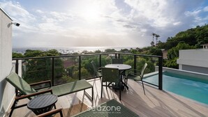 A balcony with a pool, chairs, and a table overlooking a scenic view. - Charming Studio in Santo Antonio Mal0105 (Florianópolis)