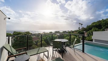 Un balcón con piscina, sillas y una mesa con vistas panorámicas.