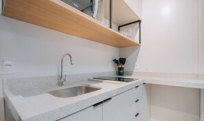A modern kitchen with a double sink, wooden shelf, and a black utensil holder.