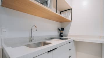 Cocina moderna con pileta doble, estante de madera y un organizador negro para utensilios.