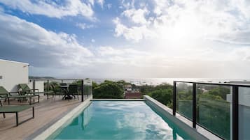 Una piscina infinita en la azotea con vistas despejadas al mar y barcos.