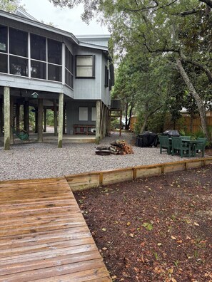 A two-story building with a covered deck area, a fire pit, and outdoor seating.