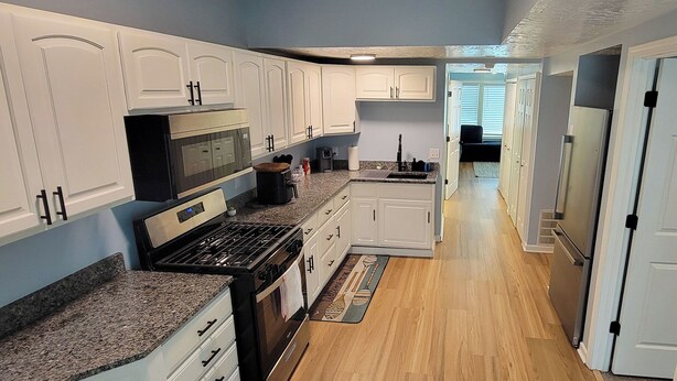 A kitchen with white cabinets, a stove, and a microwave. - 2nd Floor Lakeview 2-Bedroom Condo in Geneva U4 (Geneva)