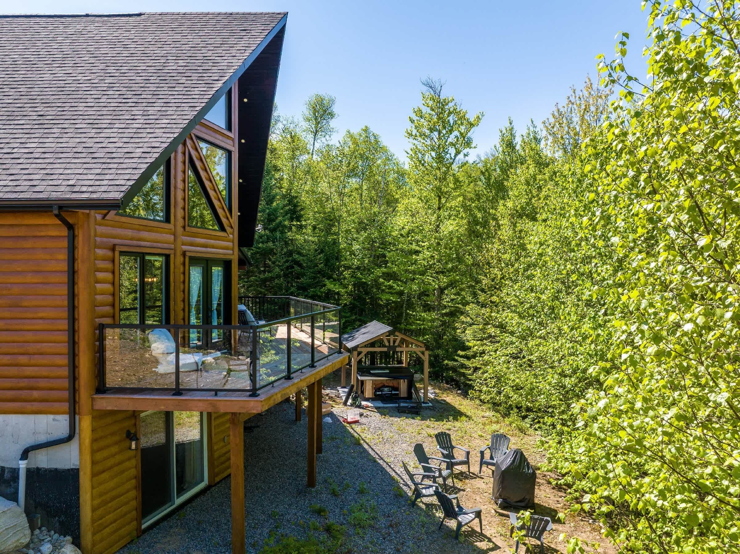 Une cabane en rondins dotée d’un balcon, d’un espace salon extérieur et d’un foyer.