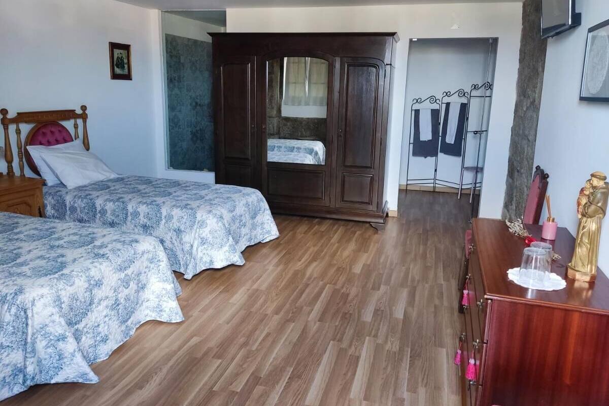 Un dormitorio con dos camas, un armario y un escritorio con una estatua.