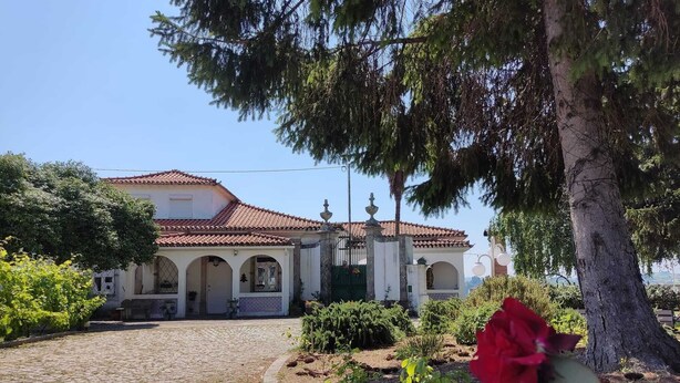 A traditional building with a tiled roof, arched windows, and a cobblestone pathway leading to the entrance. - Casa da Real Companhia (Lamego)