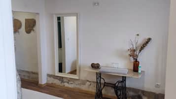 A bedroom with a bed, a small table, a mirror, and a plant.