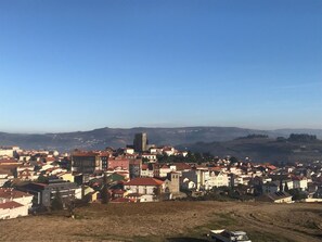 Un poble amb edificis històrics, una torre destacada i un paisatge amb muntanyes de fons.