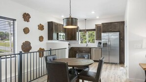 A modern kitchen with dark wood cabinets, stainless steel appliances, and a round dining table with chairs. - Modern 2-bedroom house with WiFi, AC in Kimberling City (Kimberling City)