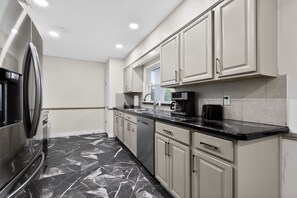 A modern kitchen with a refrigerator, dishwasher, and coffee maker.