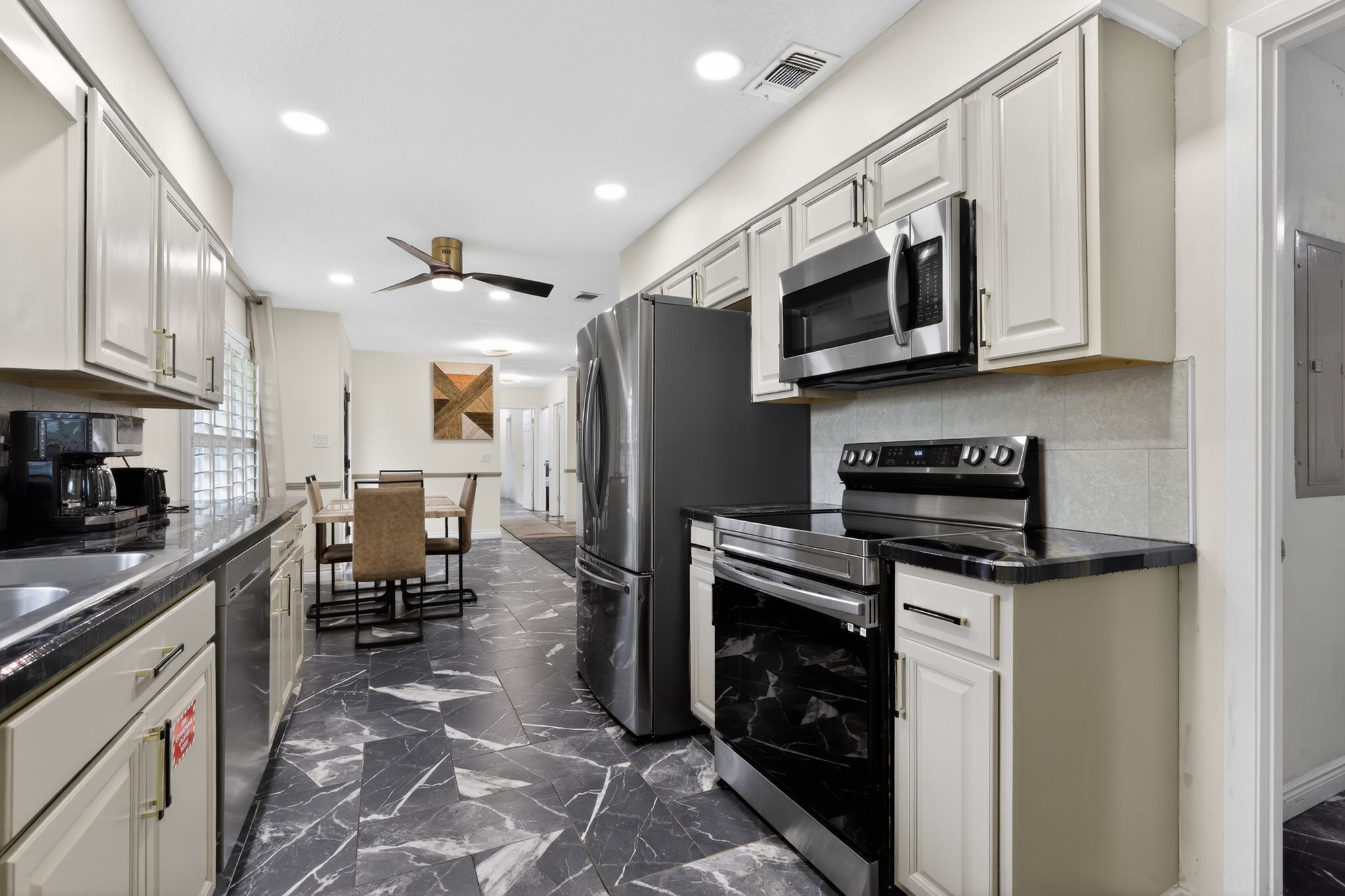 A modern kitchen with white cabinets, a black refrigerator, a microwave, and a stove.