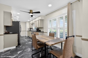 Une cuisine moderne avec un coin repas, un ventilateur de plafond et une vue sur la verdure environnante.