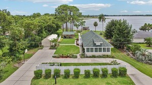 Una propiedad residencial con una casa, un porche cubierto y vista a un lago.