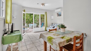 Een kamer met een eettafel, stoelen, een bank, een televisie en een raam met gordijnen.