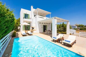 Een moderne villa met een zwembad, buitenmeubilair en een overdekt terras.