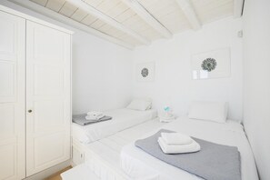 Een witte kamer met twee bedden, een kledingkast en twee kunstwerken aan de muur.