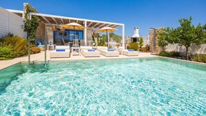 A pool area with lounge chairs and umbrellas, a stone wall, and a clear blue sky. - Villa Pollux - Two Bedroom Villa, Sleeps 4 (Gennadi)
