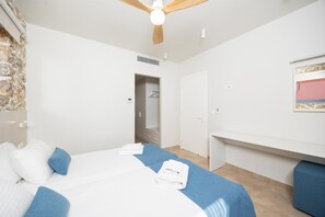 Une chambre d’hôtel équipée d’un lit, d’une armoire, d’un bureau et d’un ventilateur de plafond.