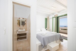 Ein Hotelzimmer mit Bad, einem Bett mit grauer Bettdecke und einem Balkon mit Aussicht.