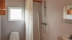 A bathroom with a toilet, a shower with a handheld showerhead, a sink, and a window. - 6 Person Holiday Park Home in Bryrup (Bryrup)