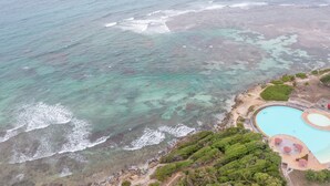 An aerial view of a coastal area with a clear blue swimming pool surrounded by greenery and a sandy beach. - La Désirade, Air-conditioned bedroom in a private estate with beach access & pool (Saint François)