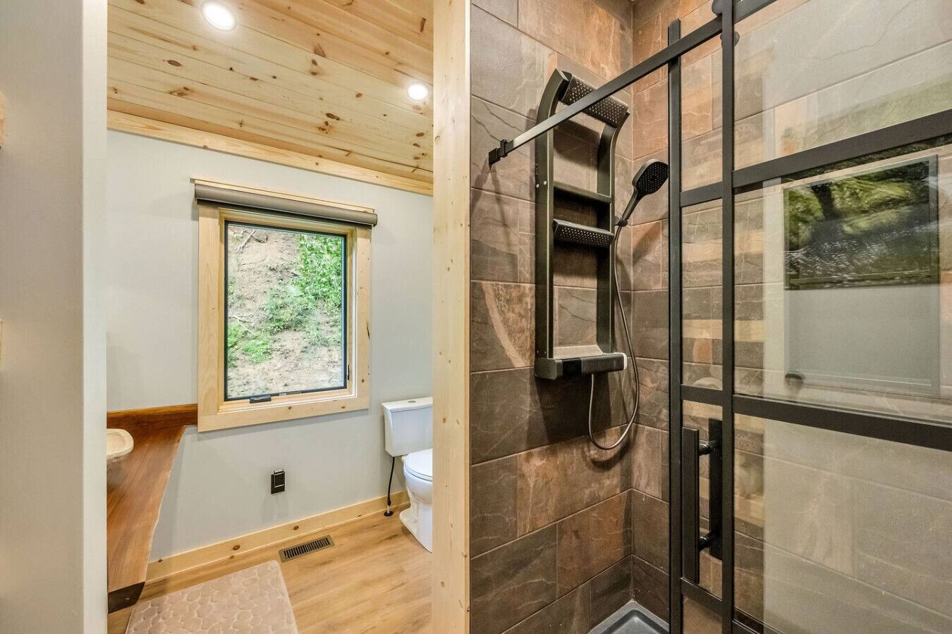 A bathroom with a window, a shower, and a toilet.