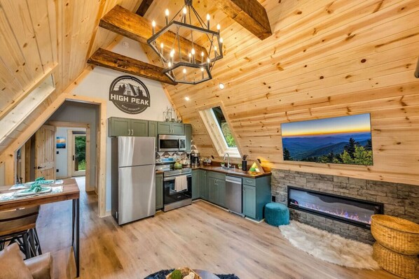 A cozy cabin interior with a kitchen, dining area, and a fireplace.