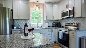 A modern kitchen with granite countertops, stainless steel appliances, and white cabinetry. - Modern Cabin, Close to Dahlonega & Wineries, View, Hot Tub, Pet Friendly (Dahlonega)