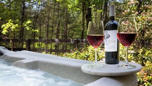A hot tub with two glasses of red wine and a bottle of wine on a stone ledge. - Modern Cabin, Close to Dahlonega & Wineries, View, Hot Tub, Pet Friendly (Dahlonega)