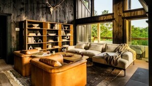A cozy living room with leather furniture, a large bookshelf, and a view of greenery outside. - Midnight Mtn-Skyline - Private pool & theater room (Sevierville)