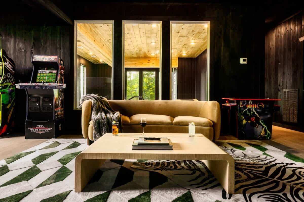 A cozy living room with a beige sofa, a coffee table, and a large window offering a view of trees.