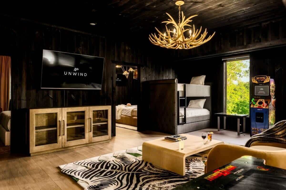Una sala de estar moderna con una televisión, una ara ña, un sofá, una mesa de centro y una estantería.