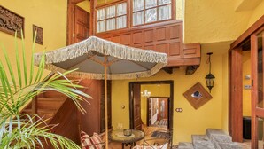 A cozy courtyard with a wooden staircase, a table with chairs, and a large umbrella. - Casa Carmen – Historic Holiday Home with Teide and Sea Views in La Matanza de Acentejo (La Matanza de Acentejo)
