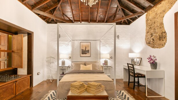 A four-poster bed with a canopy, a desk with a chair, a bookshelf, and a chandelier. - Casa Carmen – Historic Holiday Home with Teide and Sea Views in La Matanza de Acentejo (La Matanza de Acentejo)