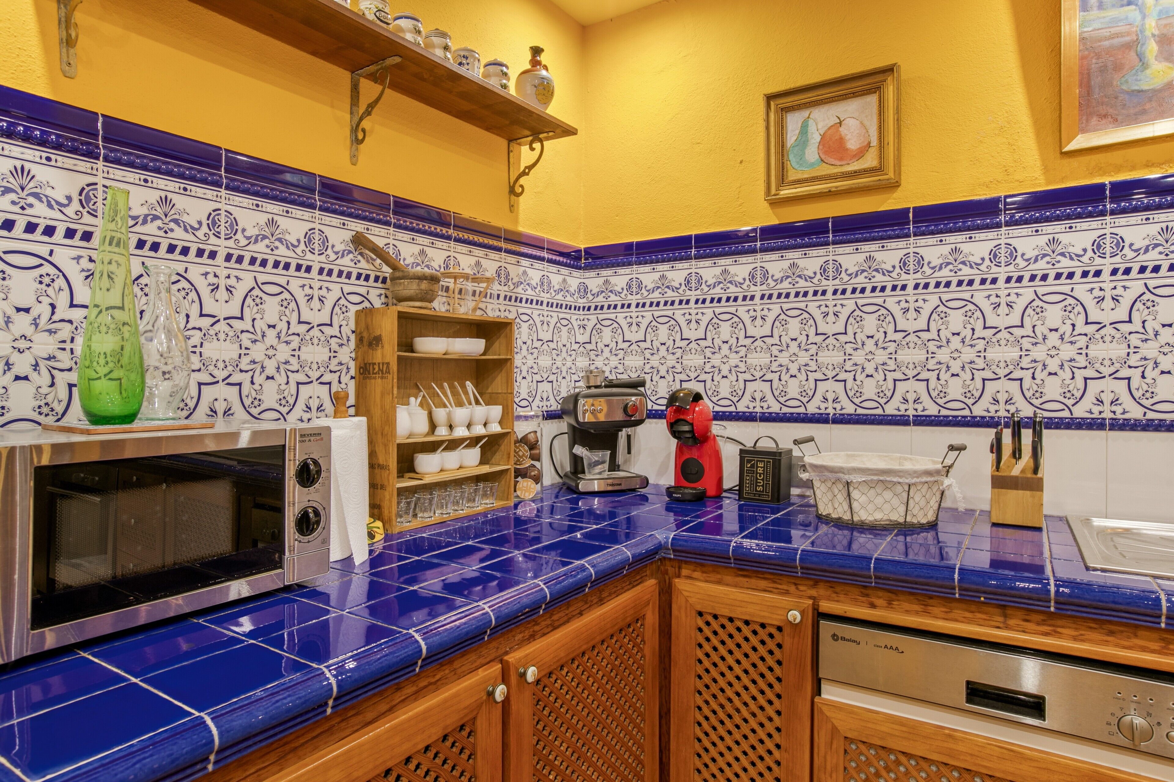 Une cuisine avec des carreaux bleus, un four à micro-ondes, une machine à café et des placards en bois.