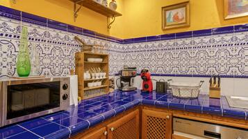 Une cuisine avec des carreaux bleus, un four à micro-ondes, une machine à café et des placards en bois.