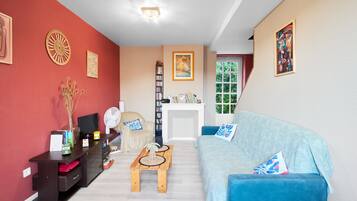 A living room with a red wall, a blue sofa, a wooden coffee table, a bookshelf, and a fireplace.