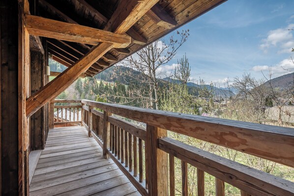 A wooden deck with a railing overlooking a mountainous landscape.