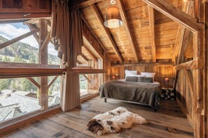 Quarto acolhedor de cabana de madeira com uma cama, uma janela e vista para as montanhas.