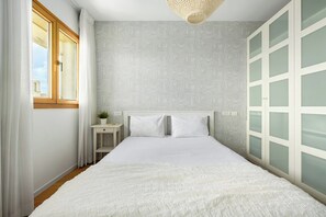 Ein Schlafzimmer mit einem Bett, einem Nachttisch, einem Fenster und einem Kleiderschrank.