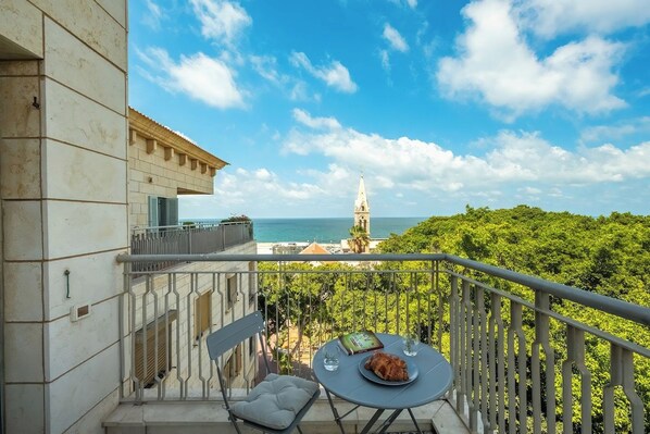 A balcony with a table, chair, and a book. A tower is visible in the distance.