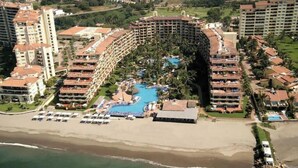 A resort with a central pool, multiple hotel buildings, and a beach.