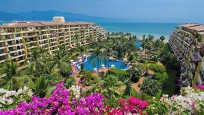 A resort with multiple buildings, a central pool, and a view of the ocean.