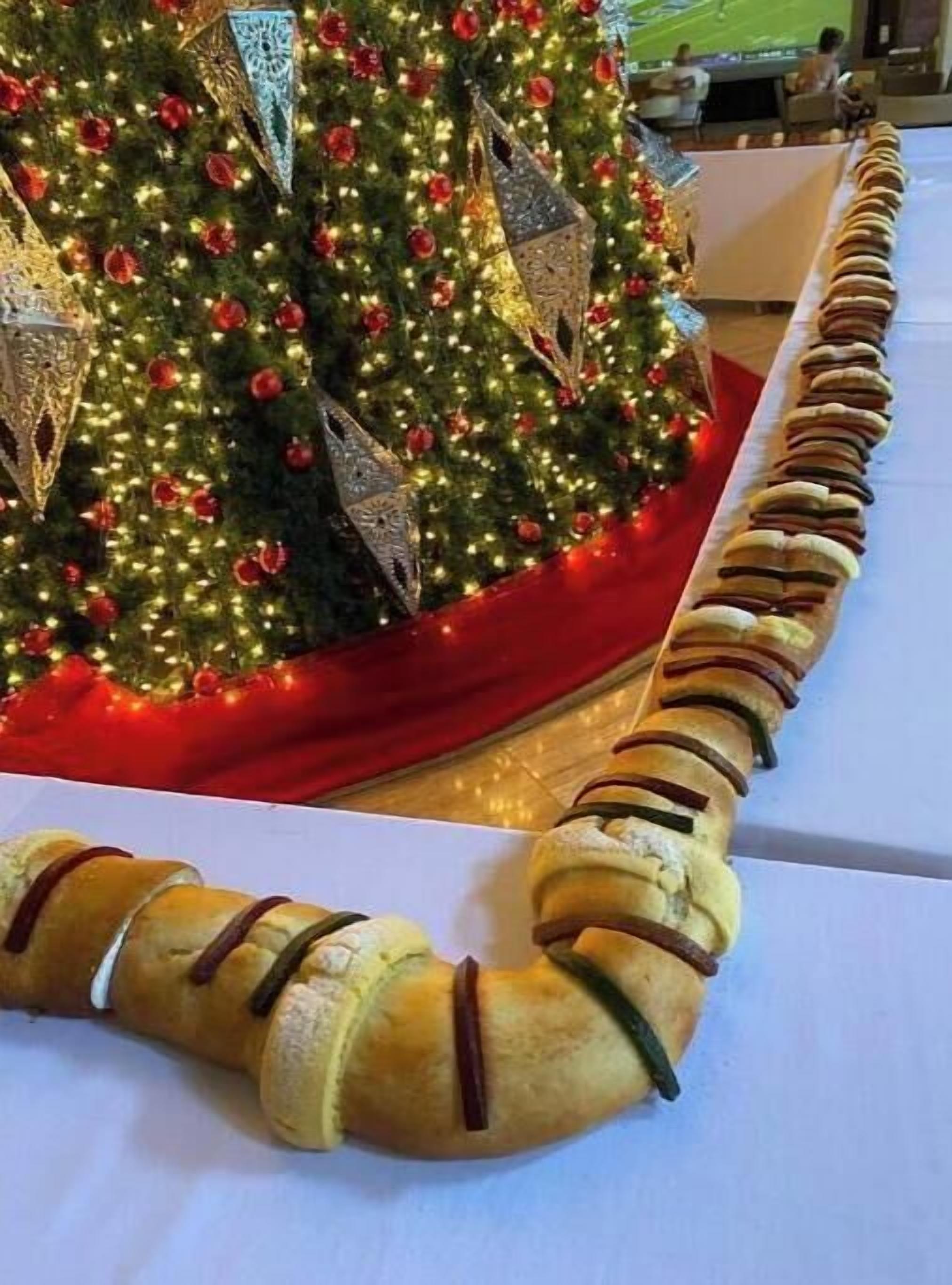 Un árbol de Navidad con luces y adornos, y un arreglo decorativo de panecillos.