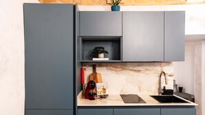 Una cocina moderna con armarios grises, encimera de mármol, cafetera, libro de cocina y un lavabo.