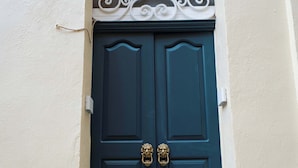 Una puerta azul oscuro con dos aldabillas de bronce, un adorno metálico encima y una ranura para correo a la izquierda.