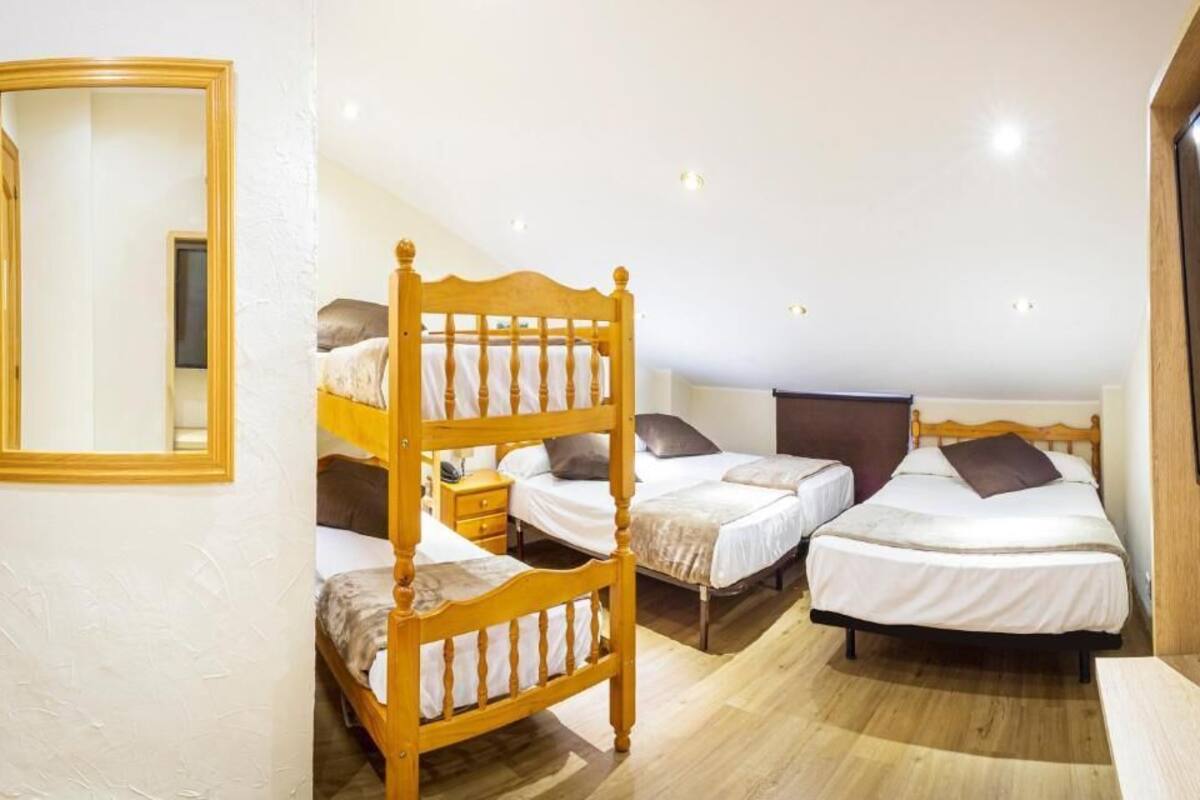 Ein Zimmer mit Etagenbetten, einem Holzkopfteil, einem Nachttisch und einem Fernseher.