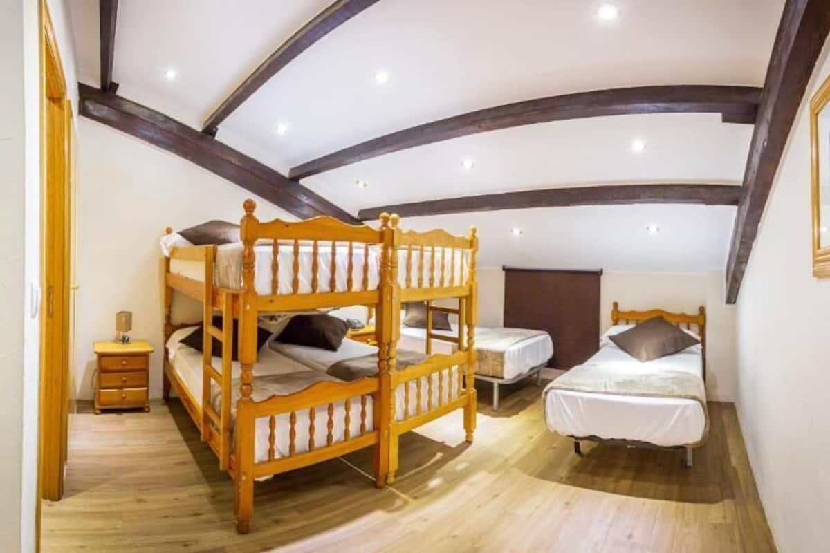 Ein Schlafzimmer mit Etagenbett, einem Einzelbett, einem Nachttisch und einem gerahmten Bild an der Wand.